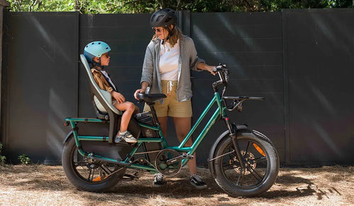 Kobieta korzysta z roweru elektrycznego Fiido T2 z zamontowanym z tyłu fotelikiem dziecięcym.