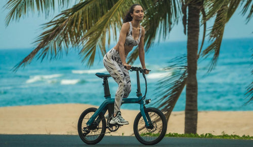 Wysportowana kobieta jeździ na rowerze elektrycznym fiido D11 po plaży.