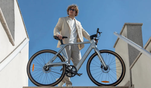 Mężczyzna jedzie po mieście na elektrycznym rowerze Fiido Air z ramą z włókna węglowego.