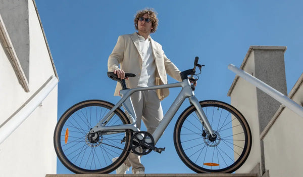 Mężczyzna jedzie po mieście na elektrycznym rowerze Fiido Air z ramą z włókna węglowego.
