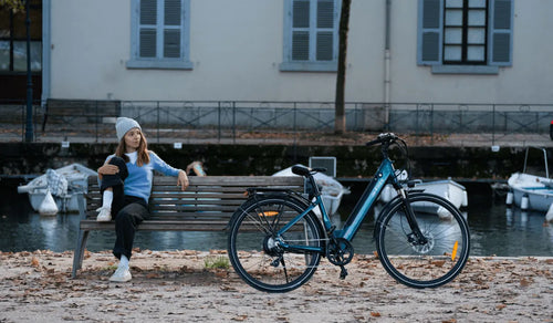 Kobieta siedzi na krześle i patrzy na swój rower elektryczny fiido c11