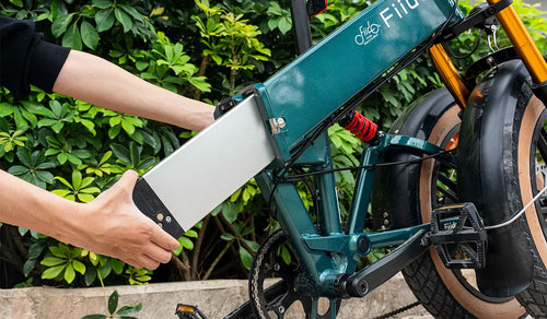 Mężczyzna wyjmuje zewnętrzny akumulator roweru elektrycznego Fiido M1 PRO.