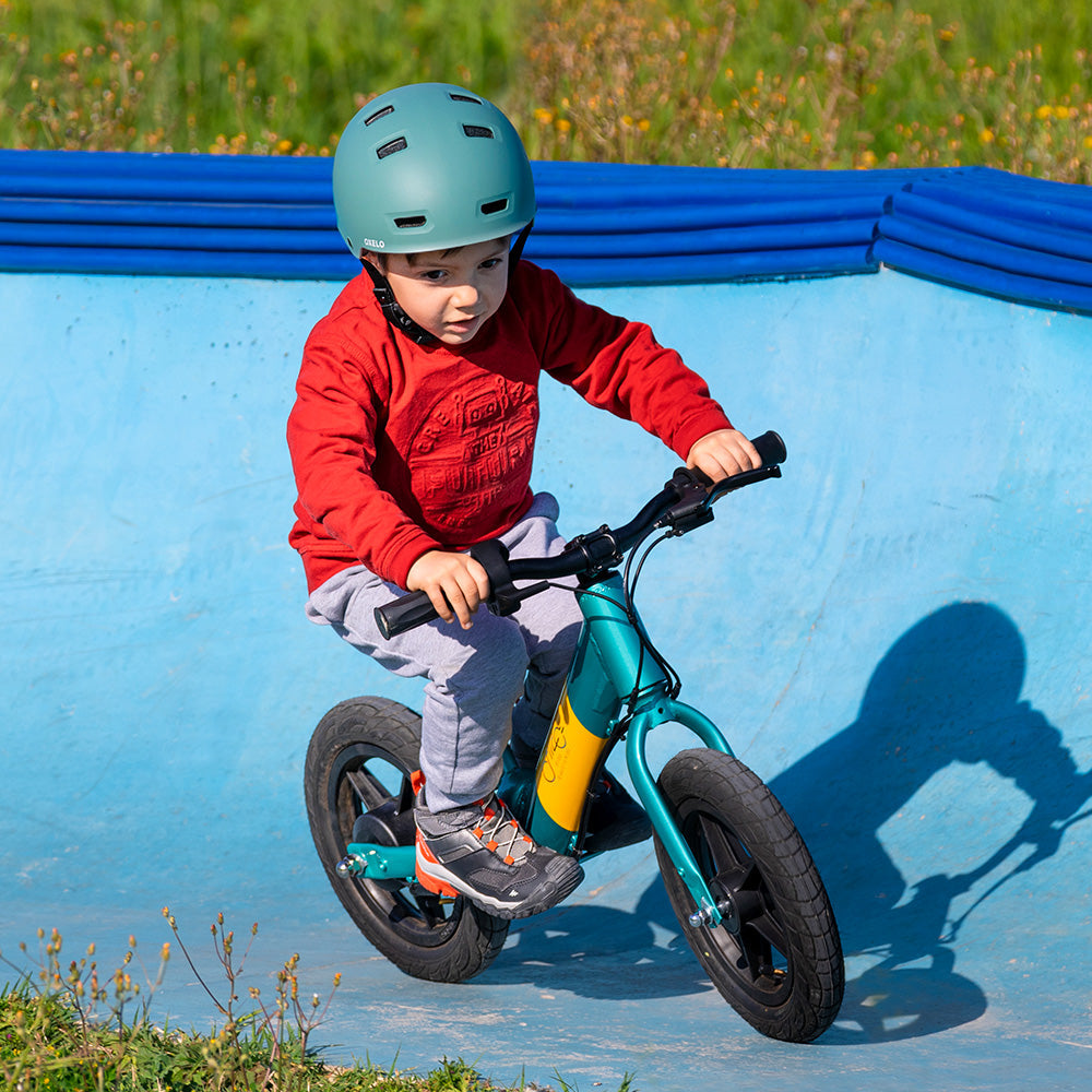 Dzieci noszą kaski i jadą na Fiido Kidz elektrycznym rowerku biegowym